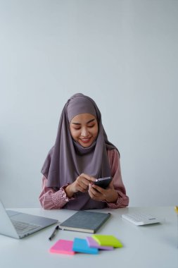 Müslüman kadın çalışan. Ofisteki müşterilerle konuşmak için telefonu kullanıyor.