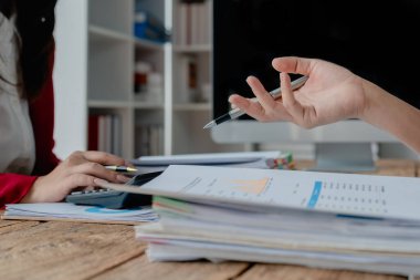 İki iş adamı iş yerinde konuşmak ya da pazarlama işini tartışmak için kağıt, hesap makinesi ve bilgisayar kullanarak buluşuyor.