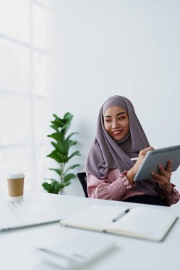 Müslüman kadınlar iş yerindeki hesaplarını kontrol etmek için tablet bilgisayar ve dizüstü bilgisayar kullanıyorlar