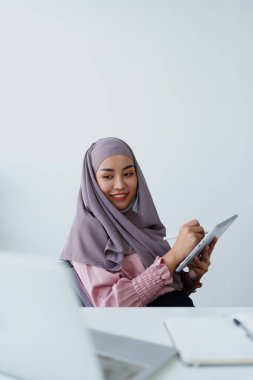 Müslüman kadınlar iş yerindeki hesaplarını kontrol etmek için tablet bilgisayar ve dizüstü bilgisayar kullanıyorlar