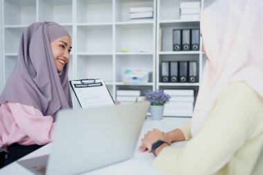 Müslüman kadın çalışanlar önemli belgeleri saklar ve müşterilerle anlaşmaları tartışırlar