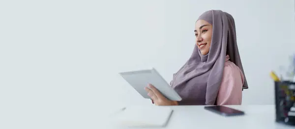 Muslim women use tablet computers, and laptops to check their accounts at work