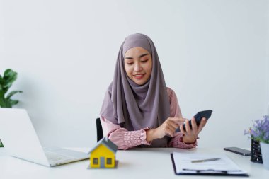 tesettürlü müslüman kadın hesap makinesi kullanarak kamu hizmetleri faturalarına odaklanıyor. Aylık çek makbuzunu hesaplayın.