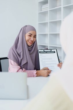 Müslüman kadın çalışanlar önemli belgeleri saklar ve müşterilerle anlaşmaları tartışırlar