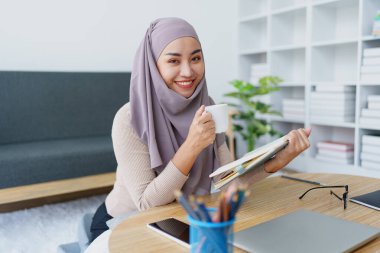 Müslüman üniversite öğrencisi evde okurken kahve içiyor.
