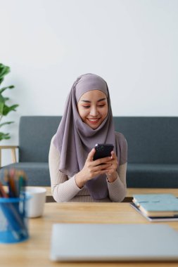 Müslüman üniversite öğrencisi arkadaşlarıyla iletişim kurmak için cep telefonu kullanıyor