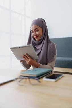 Kadın Müslüman çalışan ofiste çalışmak için tablet kullanıyor