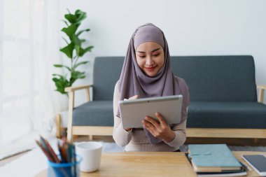 Kadın Müslüman çalışan ofiste çalışmak için tablet kullanıyor
