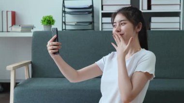Yakışıklı Asyalı kadın, evde tatildeyken tatlı bir öpücük pozu vermek için telefonunu kullanıyor. Yüksek kalite 4k görüntü