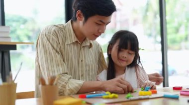 Çizim yapmak için fırça kullanan bir erkek öğretmenle resim yapan yakışıklı bir Asyalı kız. Yüksek kalite 4k görüntü