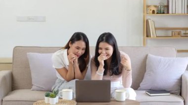 İki güzel Asyalı kız heyecanlı ifadeli bilgisayar kullanıyor. Yüksek kalite 4k görüntü