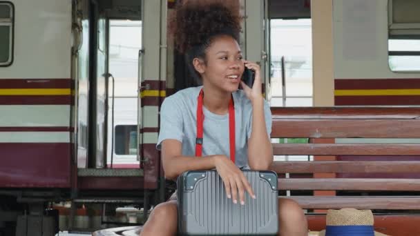 駅で電車を待っている間 アジア系の10代の少女アフリカ系アメリカ人がスマートフォンの携帯電話を使って旅行しています 高品質4K映像 — ストック動画