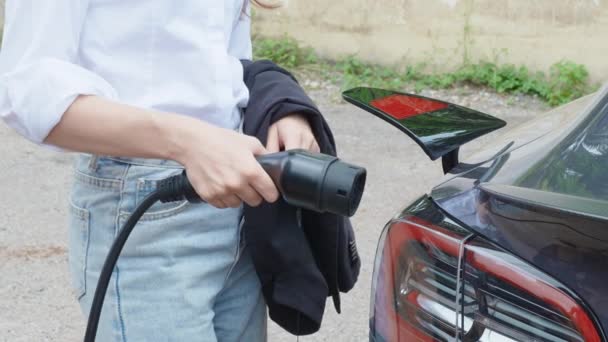 现代电动汽车充电器由穿着白衬衫的女性连接到电动汽车上 慢动作中被击中 高质量的4K镜头 — 图库视频影像