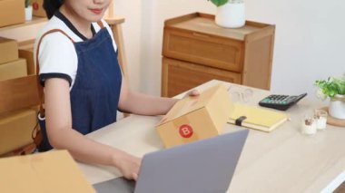 A portrait of a small startup, an SME owner, an Asian female entrepreneur checking orders to arrange the produce before packing the products in the inner boxes with the customers. Freelance concepts