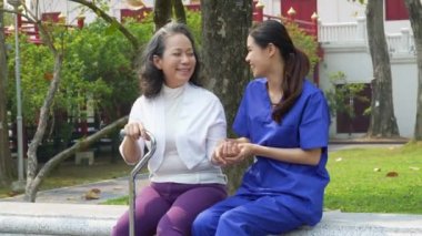 Sağlık hemşiresi, dışarıda yaşlı bir kadınla fizik tedavi, genç hemşire bacak kaslarını güçlendirmek için yaşlı insanlarla ilgileniyor. Yüksek kalite 4k görüntü
