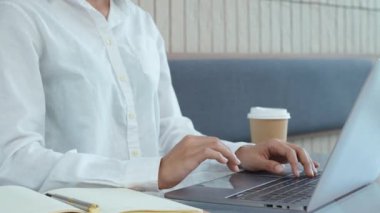 Bilgisayarda çalışan genç Asyalı bir kadın ve elinde bir kafedeki not defterine not almak için kalem tutuyor. Yüksek kalite 4k görüntü