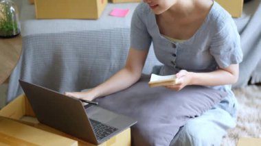 Bağımsız genç Asyalı kadın çevrimiçi satıcının küçük işletme girişimciliğine başlamak, bilgisayar kullanmak ve müşterilere dağıtım için ürünleri paketlemek için siparişler almaktır. KOBİ teslimat konsepti. Yüksek kalite