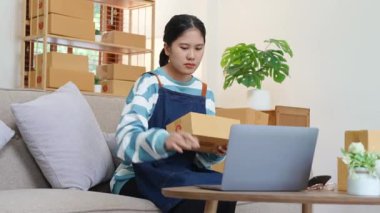 A portrait of a small startup, an SME owner, an Asian female entrepreneur checking orders to arrange the produce before packing the products in the inner boxes with the customers. Freelance concepts