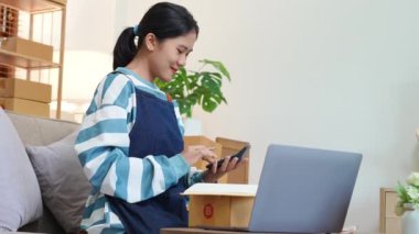 Serbest çalışan Asyalı bir kadının işletme karını hesaplamak için dizüstü bilgisayar ve hesap makinesi kullanarak küçük bir iş kurması. Online pazarlama paketi öğeleri ve KME konseptiyle. Yüksek kalite