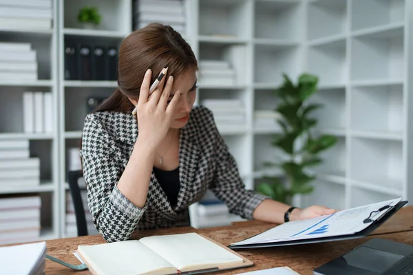 stock image female employee holds a pen and checks investment financial documents