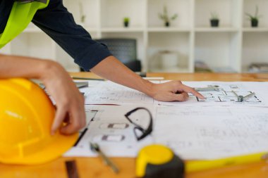 Mühendisler planlı çizim ve ofis tasarım projesini tartışıyorlar.