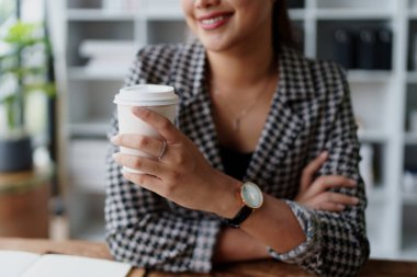 Bilgisayarda konuşan ve kahve içen bir iş kadını portresi..