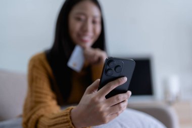 Kadın internet üzerinden alışveriş yapmak için kredi kartını kullanıyor, akıllı telefonundaki çeşitli mağazaları geziyor..