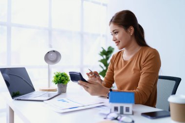 Hesap makinesi, bilgisayar ve belge kullanan Kadın Ev Finansmanı Yönetimi Hesaplama için ipotek.