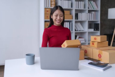 Kadın, çevrimiçi satıcı, e-ticaret platformu üzerinden müşteri siparişlerini ve teslimatlarını etkili bir şekilde yönetiyor..