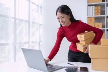 Kadın, çevrimiçi satıcı, tablet bilgisayar kullanarak e-ticaret platformu üzerinden müşteri siparişlerini ve teslimatlarını etkili bir şekilde yönetir..