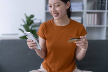 Kadın internet üzerinden alışveriş yapmak için kredi kartını kullanıyor, akıllı telefonundaki çeşitli mağazaları geziyor..