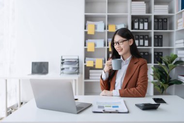 Bir iş kadını mali işlerine ara verip işine devam etmeden önce bir fincan kahve içip dinlenir.