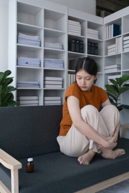 Evdeki kanepede oturan kadın depresyonla mücadelesinin sembolü olan ilaç şişesine baktı..