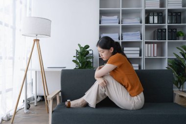 Evdeki kanepede oturan kadın depresyonla mücadelesinin sembolü olan ilaç şişesine baktı..