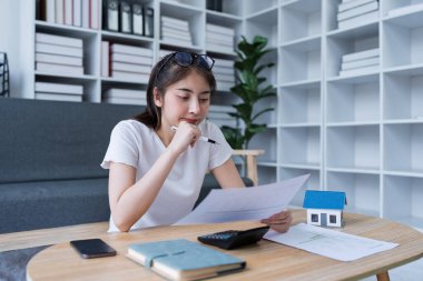 Gayrimenkul yatırımlarının giderlerini hesaplarken düşünceli kadın belgeleri gözden geçiriyordu..