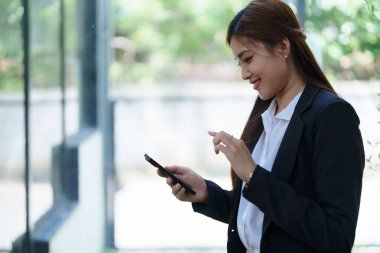 Profesyonel iş kadını, ofiste hisse senedi pazarlama grafikleri, defter ve dizüstü bilgisayar kullanarak finansmanı hesaplamak için hesap makinesiyle akıllı telefon görüşmesi yaptı..