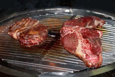 Izgarada çeşitli çiğ et parçaları var..