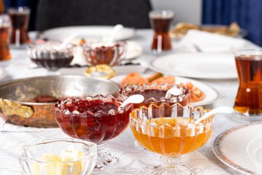 Honey and jam, blurry background and selective focus on honey and jam. Butter, frying pan, Turkish tea and breakfast table. Delicious food ready to be eaten. Morning routine concept idea photo.