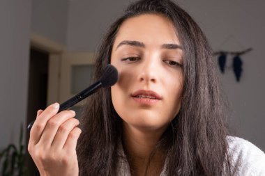 Holding make up brush, beautiful brunette caucasian girl holding make up brush. Refreshing her make up for the night. Gently open her mouth. Enjoy her skin and beauty. Skin care concept idea image.
