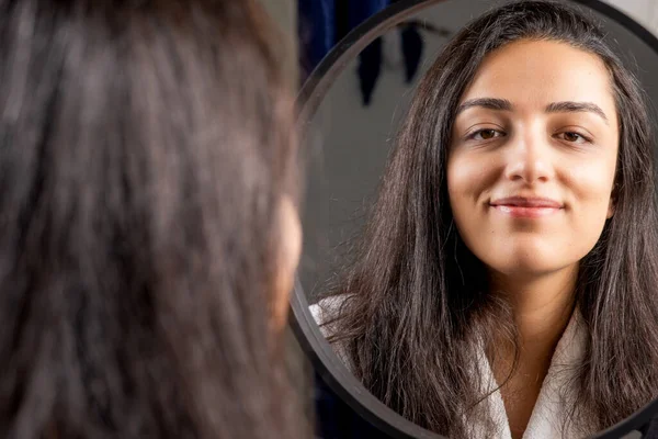 Woman self care, portrait of beautiful caucasian woman self care concept. Mirror reflection. Selective focus of brown haired girl happy smiling and looking to camera over shoulder view. Apply make up.