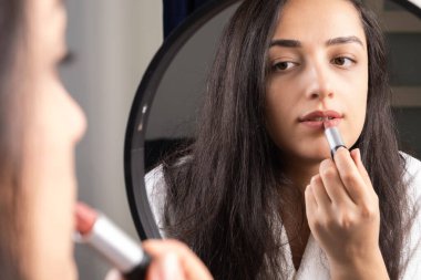 Doing make up, beautiful millennial woman looking mirror and doing make up. Brunette caucasian girl rouging lipstick. Every day morning routine. Applying beauty cosmetics concept idea image.