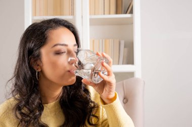 Thirsty woman, sitting at home thirsty woman. Brunette caucasian millennial dehydrated girl drinking water from glass. Recover hydration balance, closed eyes, healthy lifestyle concept idea.