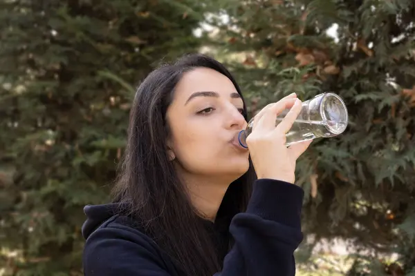 Woman drinking water, side view portrait of caucasian woman drinking water. Enjoying pure fresh mineral crystal still aqua. Thirsty girl after outdoor walking or jogging. Copy space.
