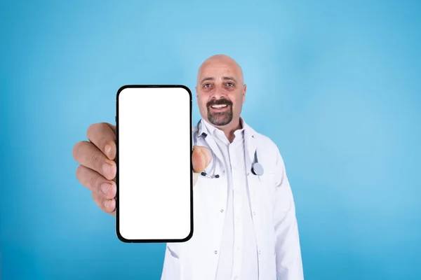 モバイル広告コンセプト 医師は モバイル広告コンセプトのための大きな空の画面スマートフォンを示しています 現代の携帯電話のモックアップ 笑顔の白人のはげ男 青の背景 コピースペース — ストック写真