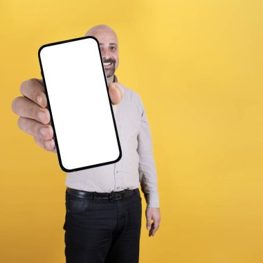 Akıllı telefon gösteriyor, mutlu, beyaz, kel adam akıllı telefon gösteriyor. Beyaz ekranlı büyük bir cep telefonu, taklit et. Mobil uygulama reklamı. Cep telefonu görüntüsü. Uzayı kopyala Turuncu arkaplan.