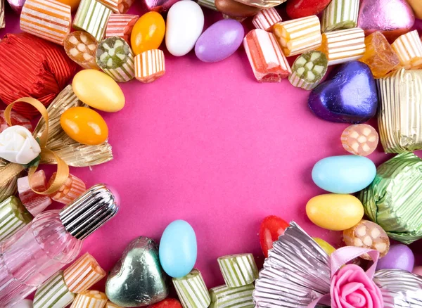 Stock image Sugar feast social media post background with copy space. Pink background. Colorful candies, wrapped luxury chocolate. Almond candy. Sugars. Little bottle of cologne. Top view. Delicious snacks.