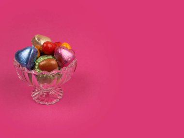 Cam kasede paketlenmiş lüks çikolatalar. Kopya alanı ile izole edilmiş pembe arka plan. Şeker Şöleni konsepti. Ramazan Bayram tebrik kartı fikri. Şık kristal fiyonkta badem şekeri.