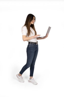 Dizüstü bilgisayar kullanarak, diz üstü bilgisayar kullanan bir kadının boy boy boy yan görüntüsü. Genç, çekici kız elinde defterle internette geziniyor. İzole edilmiş beyaz arkaplanda duruyor, boşluğu kopyala. 