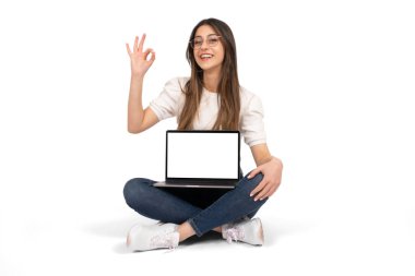 Laptop maketini hazırla, genç kız yerde oturuyor ve elinde dizüstü bilgisayarla maket yapıyor. Web sitesi öneriyor, eliyle işaret veriyor. Yeni uygulama, reklam, modern teknoloji fikri. 