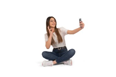 Selfie çeken bir kadın. Kafkasyalı genç bir kadının selfie çekerken uzun bir portresi. Yerde oturup, 